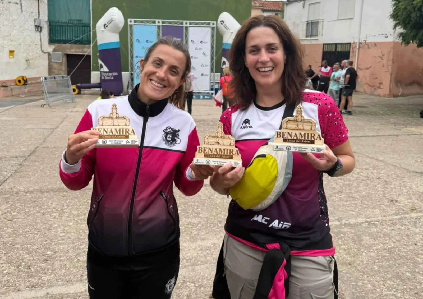 Dos corredoras muestran sus trofeos de madera con el nombre de Benamira